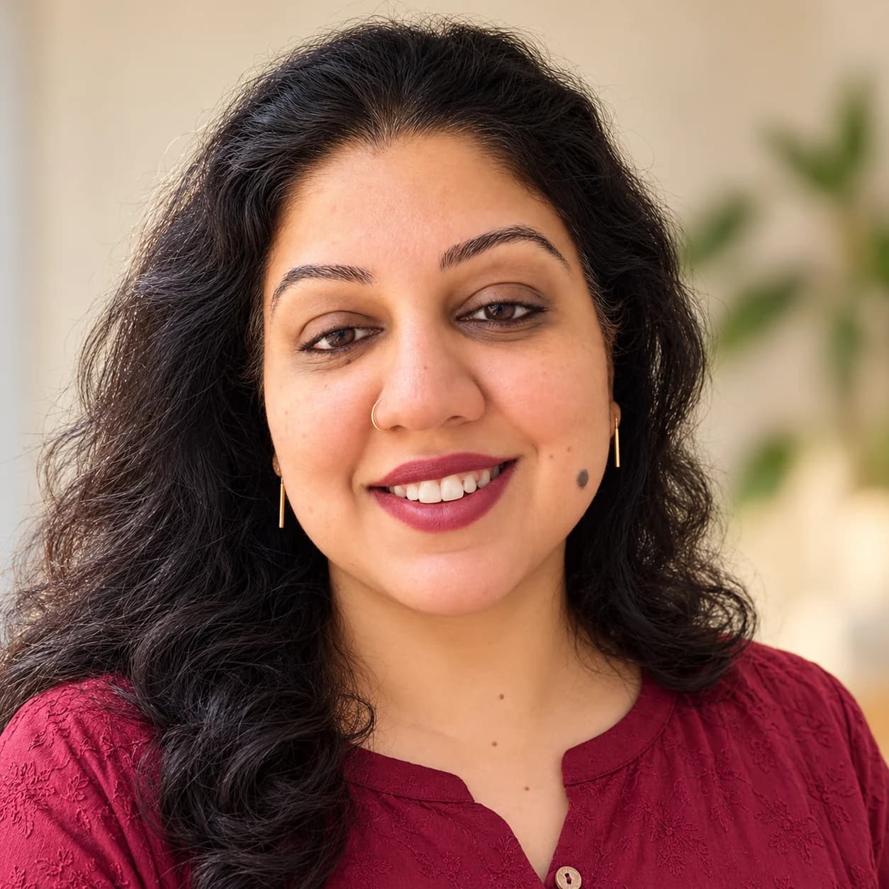 Ayushi Sharma, smiling, in a maroon top
