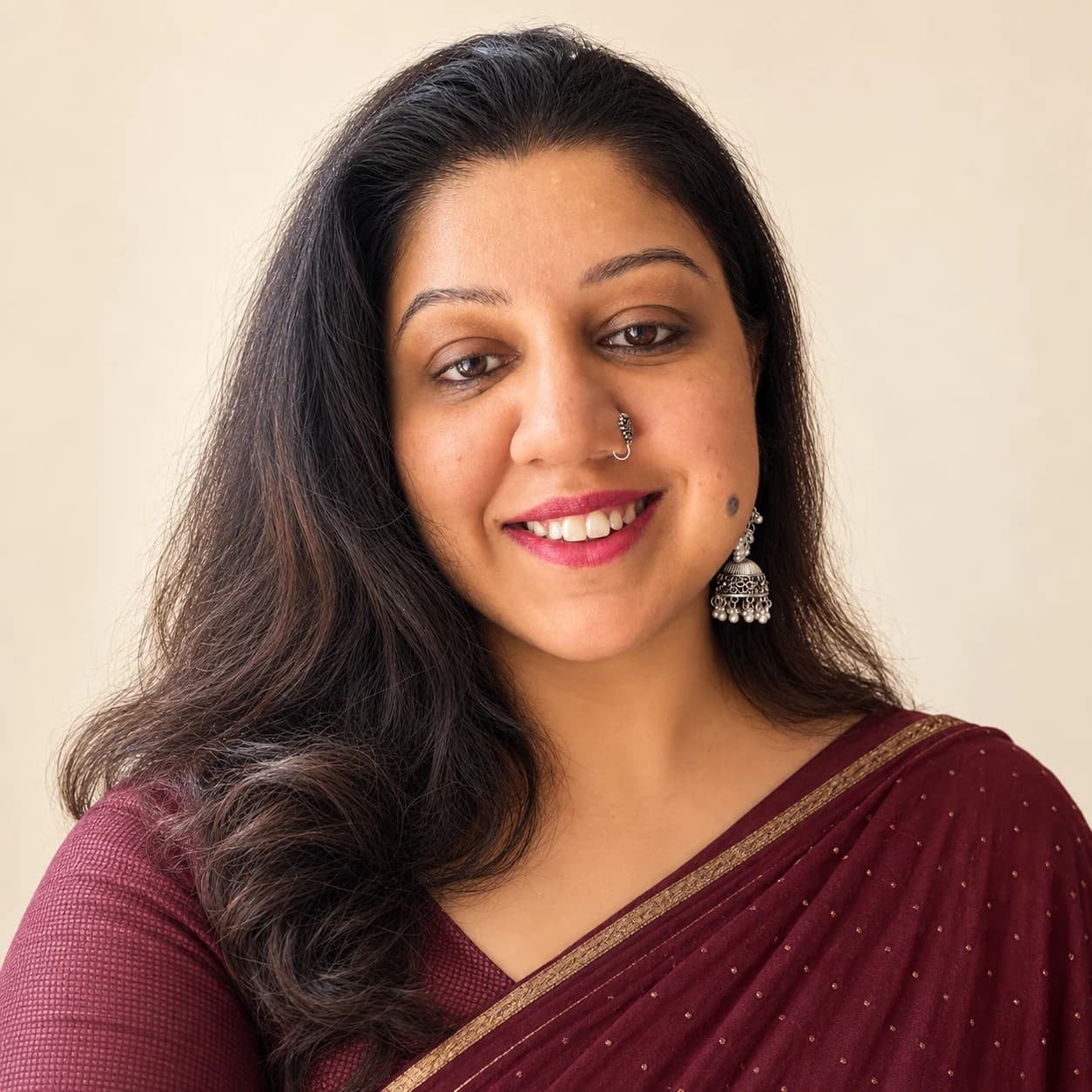 Ayushi Sharma smiling, in a maroon saree and silver earrings